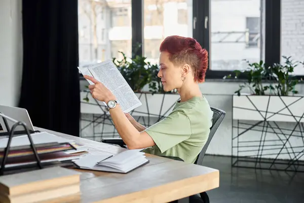 Pessoa não-binária elegante que trabalha com documentos enquanto está sentado no local de trabalho no escritório moderno — Fotografia de Stock