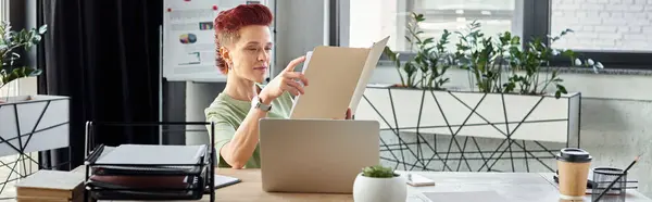 Bigender manager working with documents near laptop and coffee to go in office, horizontal banner — Stock Photo