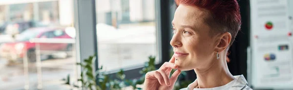 Pensive and smiling non-binary manager in casual attire standing and looking away in office, banner — Stock Photo