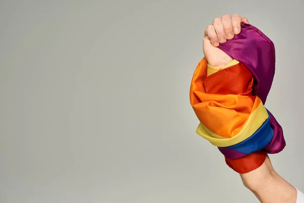 Vista recortada de la mano de una persona no binaria con bandera LGBT sobre fondo gris con espacio para copiar - foto de stock