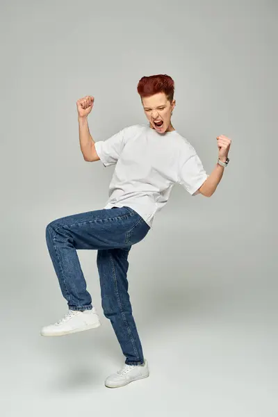 Excited queer person in white t-shirt and jeans shouting and gesturing on grey backdrop, full length — Stock Photo