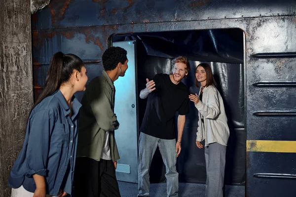 Cheerful young man gesturing and inviting friends to subway wagon inside of escape room, quest — Stock Photo