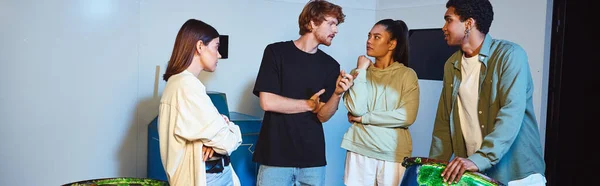 Banner of interracial group of friends chatting near rusty barrels and solving quest in escape room — Stock Photo