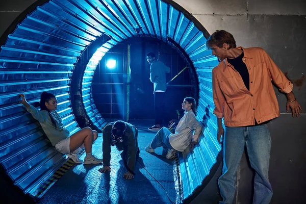 Різноманітна група друзів, які беруть участь у захоплюючій квест-кімнаті пригоди в тунелі з блакитним світлом — стокове фото