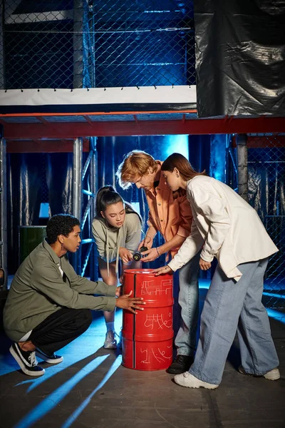 Group of four young and multicultural friends collaborate on clue in escape room game, quest — Stock Photo