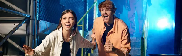 Scared couple running from freaky people in gas masks and orange ppe suits in escape room, banner — Stock Photo