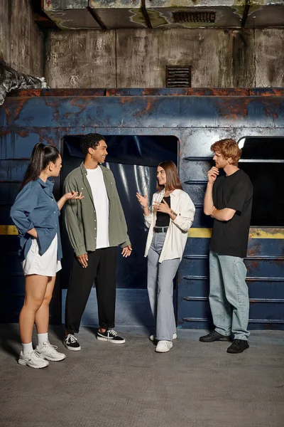 Group of four happy multicultural friends deciding on strategy in an underground quest room — Stock Photo