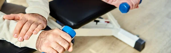 Cropped view of man working out with dumbbell near recovery specialist in kinesio center, banner — Stock Photo