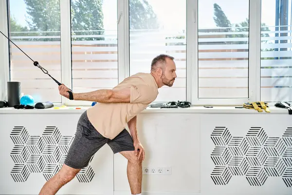 Man in sportswear working out on exercise machine in gym of modern kinesio center, recovery — Stock Photo
