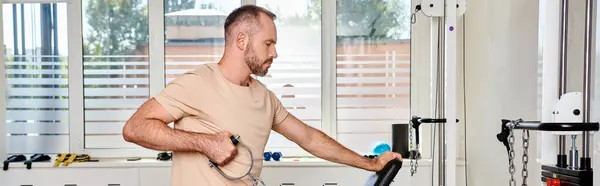 Side view of man in sportswear working out on exercise machine in kinesio center, horizontal banner — Stock Photo