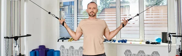 Sportlicher Mann in Sportbekleidung, der in der Turnhalle des modernen Kinesio-Zentrums trainiert, Regenerationstraining, Banner — Stockfoto