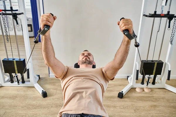 Athletic man in sportswear working out on exercise machine in kinesio center, recovery session — Stock Photo
