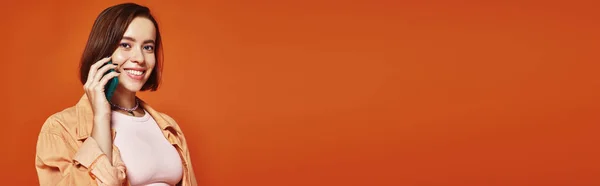 Jovem alegre em traje elegante falando no smartphone no fundo laranja, faixa de chamada de telefone — Fotografia de Stock
