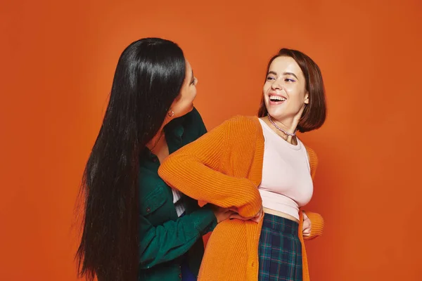 Joyful friends in casual clothing hugging and sharing happy moment together on orange background — Stock Photo