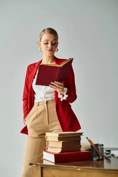Seductora mujer con cabello rubio en traje vívido leyendo junto a un montón de libros con la mano en el bolsillo - foto de stock