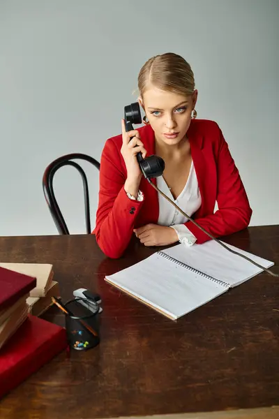 Hermosa mujer rubia en rojo elegante chaqueta hablando por teléfono retro mientras trabaja en la oficina - foto de stock