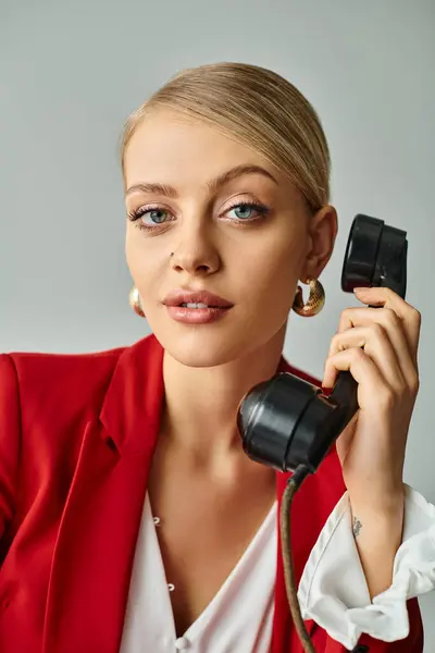Retrato de mujer atractiva alegre en chaqueta roja hablando por teléfono vintage y mirando a la cámara - foto de stock