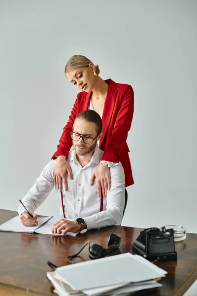 Ansprechende, fröhliche Frau in roter Jacke umarmt ihren hart arbeitenden Chef im Büro, Arbeitsangelegenheit — Stockfoto