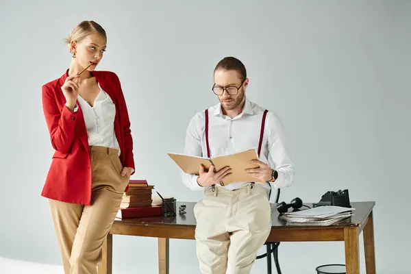 Mujer joven de buen aspecto en chaqueta roja vibrante mirando seductora a su jefe trabajador - foto de stock