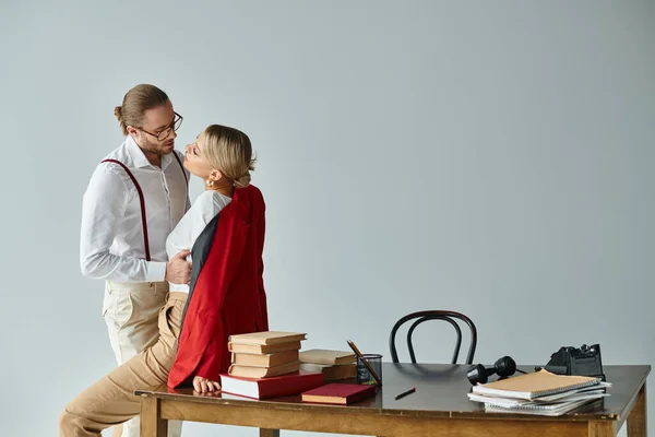 Appealing young couple in elegant attires kissing on table and looking at each other, work affair — Stock Photo