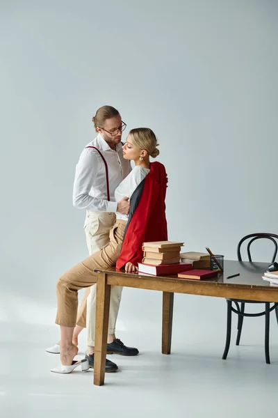 Alluring elegant couple with stylish accessories kissing on table while in office, work affair — Stock Photo