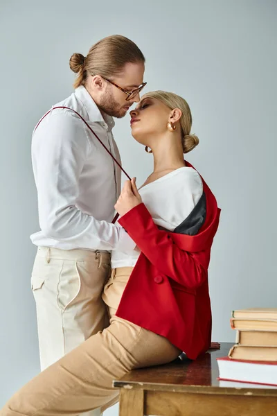 Sexy couple in vibrant attires with accessories kissing lovingly on table in office, work affair — Stock Photo