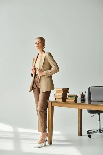 Beautiful young woman with blonde hair wearing elegant suit and looking at camera while at office — Stock Photo