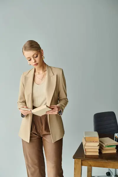 Appealing blonde woman with accessories in stylish clothes standing and reading book at office — Stock Photo