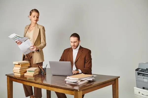 Attraente coppia dedicata in abiti eleganti lavorando sodo insieme con computer portatile e documenti — Foto stock