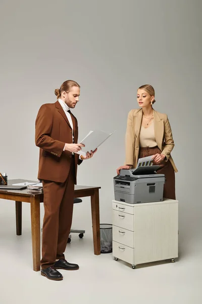 Blonde woman posing next to copy machine and looking at her hard working boyfriend, work affair — Stock Photo
