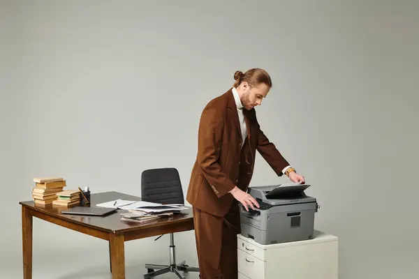 Attrayant jeune homme avec barbe et cheveux recueillis dans la veste à la mode de travail avec machine à copier — Photo de stock