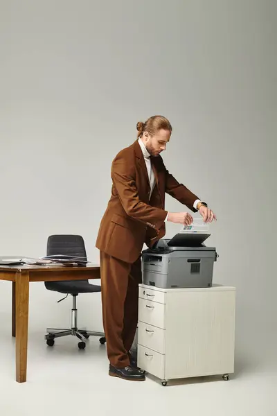 Beau jeune homme avec barbe en costume marron élégant travaillant avec photocopieuse au bureau — Photo de stock