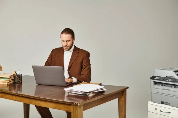 Boa aparência jovem modelo masculino com barba na jaqueta marrom elegante trabalhando duro em seu laptop — Fotografia de Stock