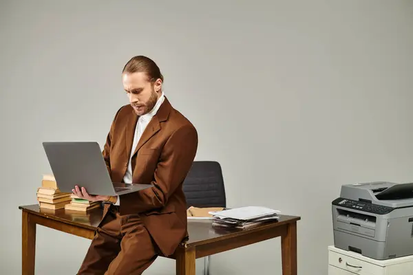 Jovem atraente com barba na jaqueta marrom elegante trabalhando em seu laptop no escritório — Fotografia de Stock