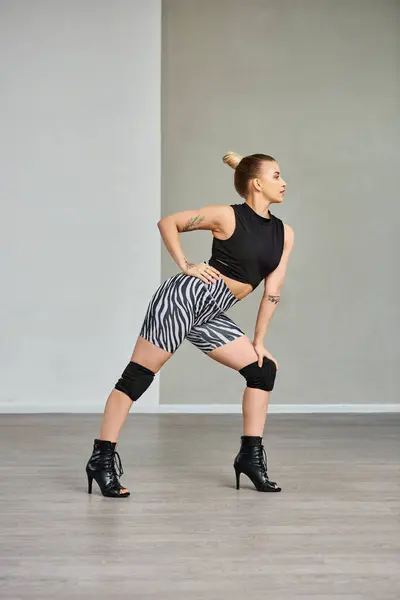 Uma dançarina graciosa se equilibra sem esforço nas pontas de seus dedos dos pés em saltos altos elegantes e top preto — Fotografia de Stock