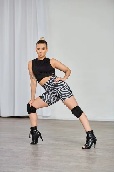 Eine anmutige Tänzerin posiert und zeigt ihre High Heels und Bewegungen gegen die Innenwand — Stockfoto
