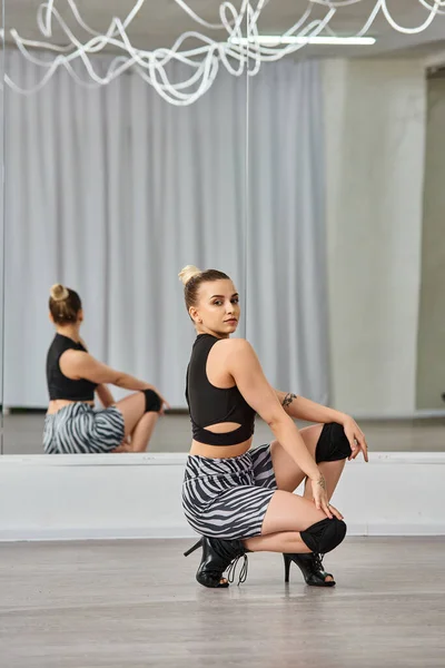 A fashion-forward woman showcases balance as she dances in her high heels and zebra print shorts — Stock Photo