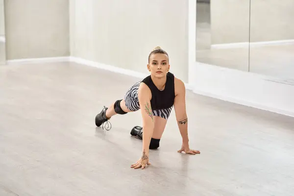 Решительная женщина балансирует на руках и ногах, танцуя на высоких каблуках в студии с зеркалом — стоковое фото