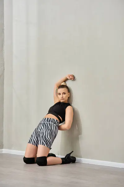 A confident woman strikes a pose against a wall, showcasing her fashionable outfit and high heels — Stock Photo