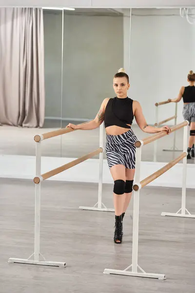 Dancer gracefully balances on the bar, showcasing her fashion-forward clothing and high heels — Stock Photo