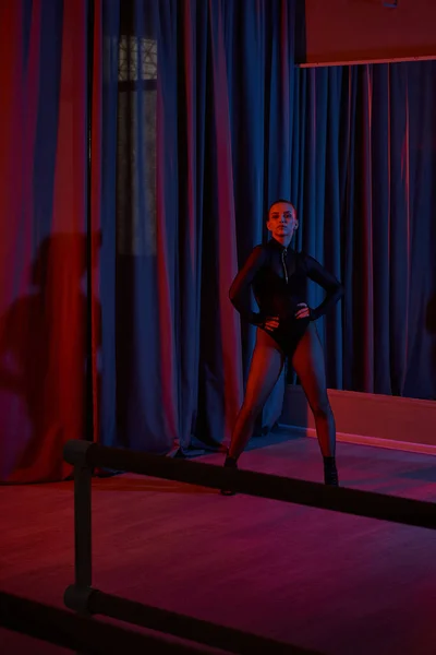Performerin posiert heftig in ihrem schwarzen Trikot und Netzstrumpfhosen, umrahmt von einem Vorhang — Stockfoto