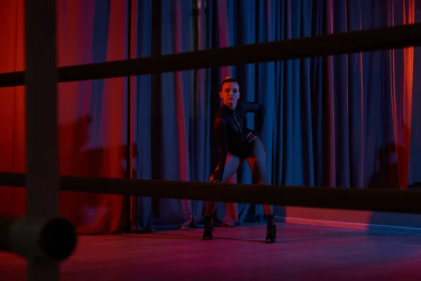Anmutige Tänzerin posiert in ihrem schwarzen Trikot und Netzstrumpfhosen, umrahmt von einem Vorhang — Stockfoto