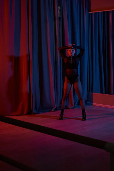 Frau in Netzstrumpfhosen und High Heels posiert während ihres Auftritts anmutig in der Nähe des Vorhangs — Stockfoto