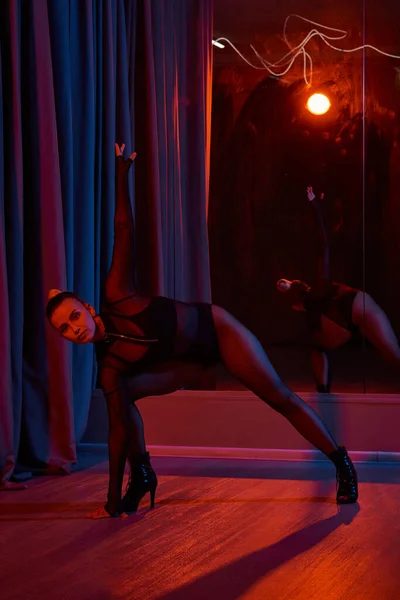 Elegante bailarina se prepara para subir al escenario, su maillot negro y tacones altos reflejándose en el espejo - foto de stock
