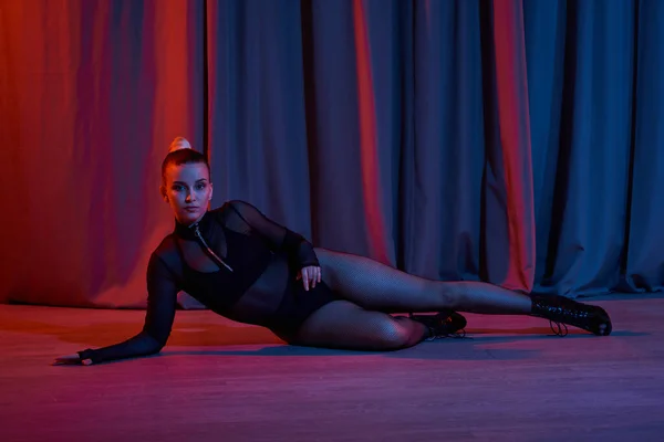 Anmutige Frau liegt auf dem Boden, umgeben von einem wehenden Vorhang, als sie ihr Talent für Tanz zeigt — Stockfoto