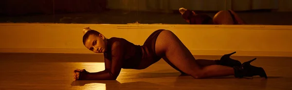 Banner einer Frau in High Heels, die ihren Körper über den polierten Boden im Tanzstudio streckt — Stockfoto