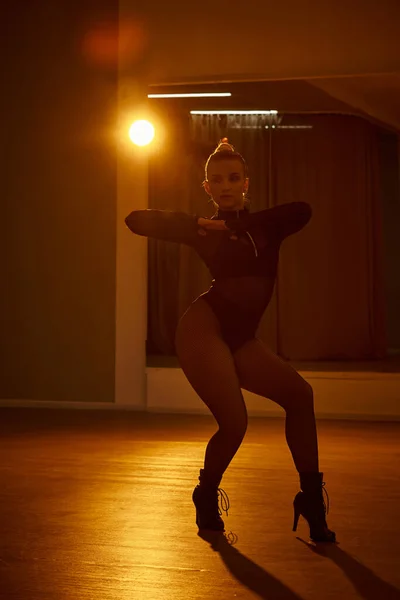 Accattivante ballerina in body nero e calze a rete si muove con grazia contro il muro — Foto stock