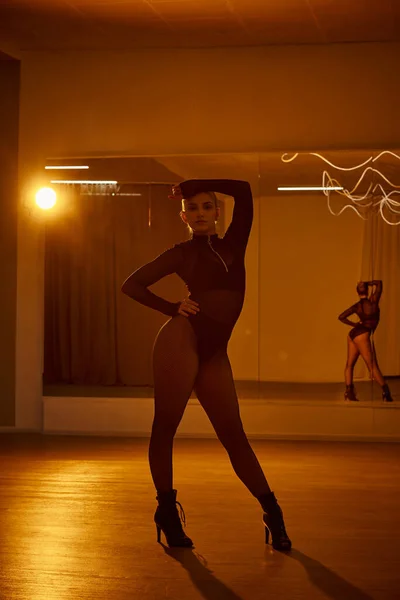 Eine Tänzerin in Netzstrumpfhose und schwarzem Trikot steht vor einem Studiospiegel auf der Tanzfläche — Stockfoto