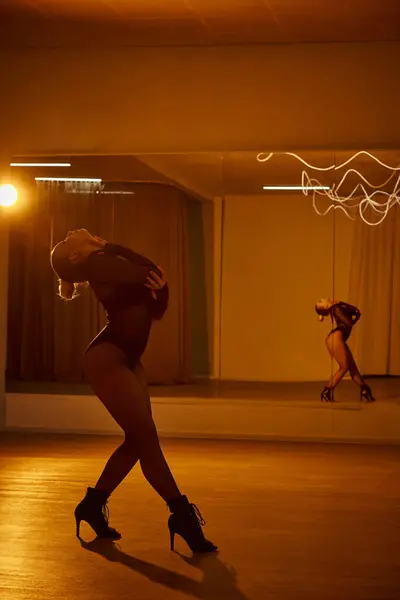 Eine Tänzerin in Netzstrumpfhose und schwarzem Trikot tanzt auf poliertem Boden im Studio — Stockfoto
