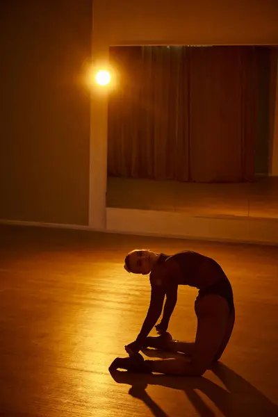 Женская изящная форма освещается окружающим светом, когда женщина танцует рядом с зеркалом — стоковое фото